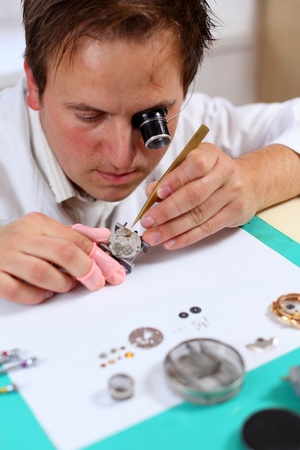 Watchmaker in his workshop repairing a wrist watch. Intentional shallow depth of fieldの写真素材