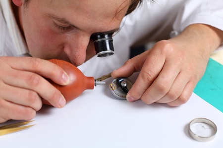 Watchmaker in his workshop repairing a wrist watch. Intentional shallow depth of fieldの写真素材