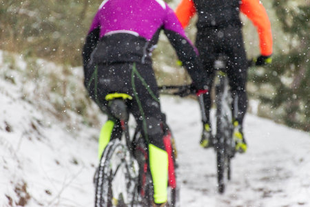 Cyclists lose their focus in the snow. Extreme mtb in the snow with the road frozen in the middle of a forest while it snows. Snowy image. Concept of extreme sport in winterの写真素材