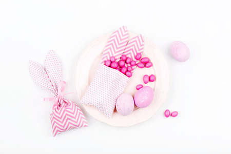 Easter table setting. Painted eggs Bunny treat bag with pink candy. Flat lay, top viewの写真素材