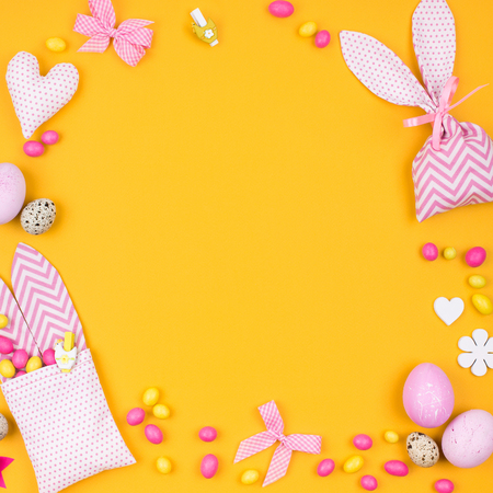 Stylish background with decoration: pink and yellow Easter eggs, fabric bunny gift bags with candies.  Kids concept. Flat layの写真素材