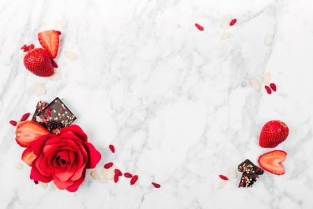 Frame of strawberry, red rose and chocolate on marble background view from above. Flat layの写真素材