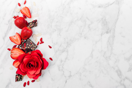 Strawberry, red rose and chocolate on marble background view from above. Flat layの写真素材