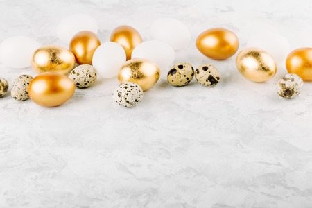 Painted Easter golden eggs and quail   eggs on a marble background. の写真素材