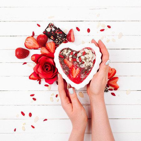 Female hands hold a strawberry smoothie in a bowl in the shape of a heart. Healthy food, Diet, Detox, Clean Eating, Vegetarian breakfast.の写真素材
