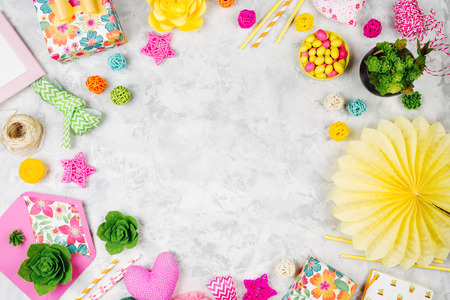 Spring background with colorful decoration. Frame with flowers, gifts, ribbons, candys and other accessories. Kids concept. Flat lay, top viewの写真素材