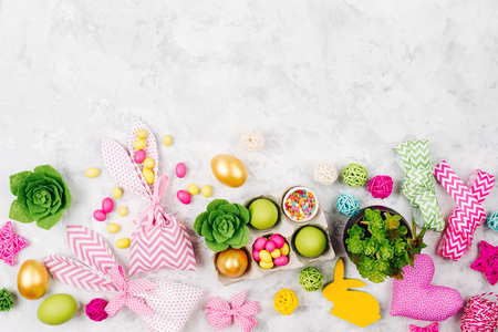 Frame border with easter decoration. Painted eggs in trays, candy, flowers, succulent with copy space. Spring background. Flat lay, top viewの写真素材