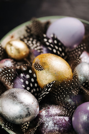 Violet, gold and silver easter eggs and beautiful decorative feathers close upの写真素材