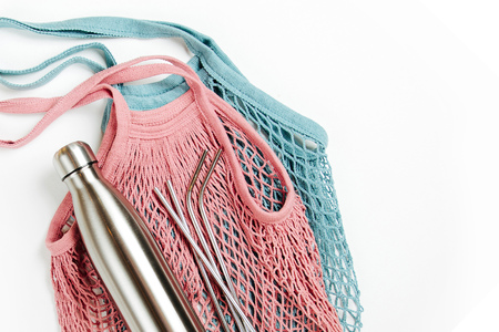Mesh bags with reusable metal water bottle on white background. Sustainable lifestyle. Zero waste concept. No plastic.の写真素材