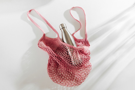 Mesh bags with reusable metal water bottle on white background. Sustainable lifestyle. Zero waste concept. No plastic.の写真素材