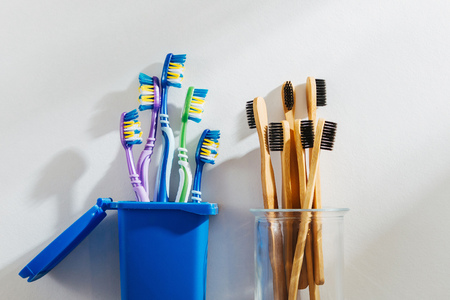 Eco friendly bamboo toothbrushes in glass and plastic toothbrushes in trash bin. Zero waste, plastic free, ecology concept.の写真素材