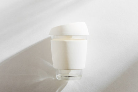White reusable eco coffee cup on white morning background.