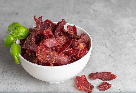 Beef Jerky, dried meat, rustic country style, delicious meat snack with fresh basil, copy spaceの写真素材