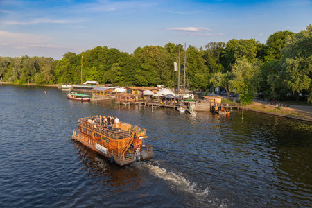 Berlin-Treptow, Germany - June 9, 2023, View of the Spree with restaurants and boat rentals in Treptower Park. The excursion boats go on the river.のeditorial素材