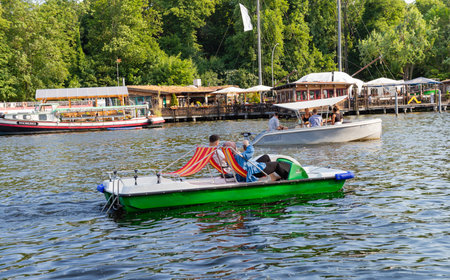 Berlin-Treptow, Germany - June 9, 2023, View of the Spree with restaurants and several boat rentals in Treptower Park. The excursion boats go on the river, copy space.のeditorial素材