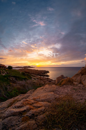 Picturesque view on colorful sky at sunset time. Jagged coastal rocks, Isola Rossa, Sardinia, Italy.