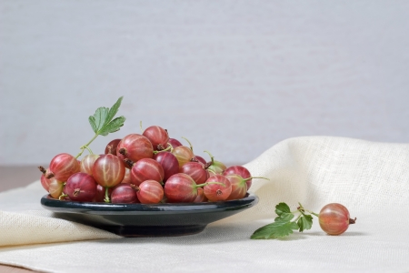 Ceramic cup with fresh gooseberries on a light backgroundの写真素材