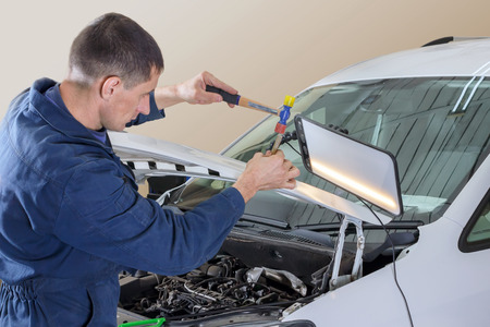 Professional mechanic removes dents on the car bodyの写真素材