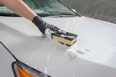 Car in the process of manual car wash with a yellow sponge and foamの写真素材