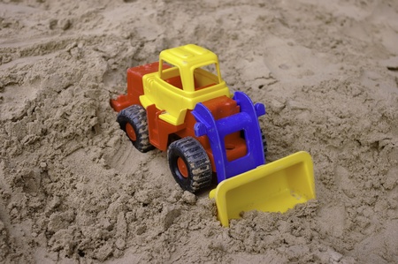 The bright-colored toy tractor on the sandの写真素材
