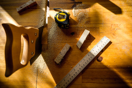 handsaw on carpentry table with meter, pencil and ruler