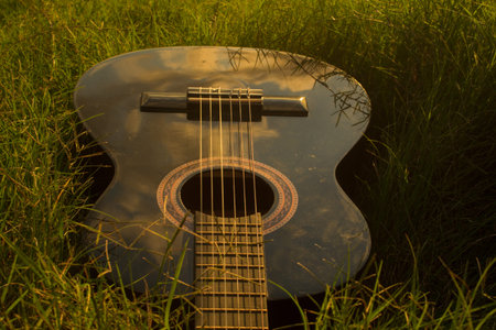 Black guitar in grass at sunset