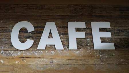 White letters spelling the word CAFE laid out on aged wooden parquet backgroundの写真素材