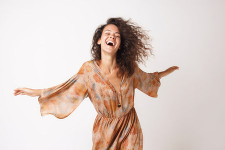 Happy young woman laughing and dancing isolated over white background in studio.の素材