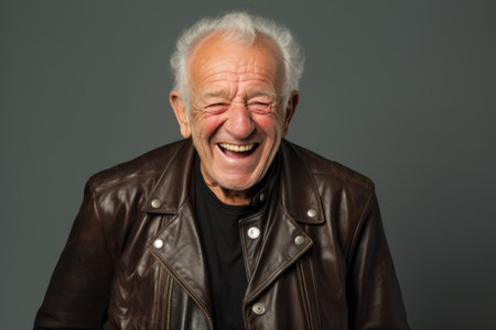 Portrait of a happy senior man in leather jacket on gray backgroundの素材