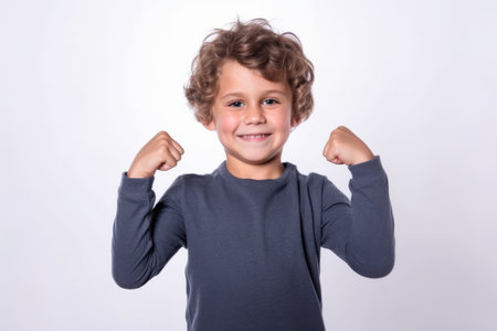 Portrait of a cute little boy with curly hair showing his musclesの素材