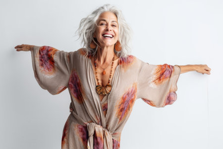 Portrait of a happy senior woman standing isolated over white background, arms outstretchedの素材