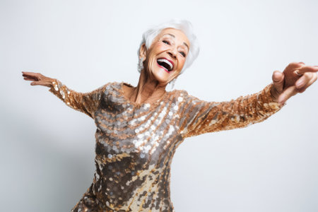 Portrait of a happy senior woman dancing against a white background.の素材
