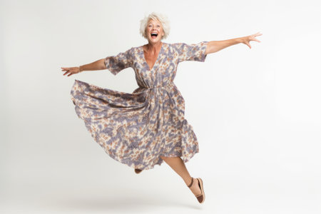 Full length portrait of a happy senior woman jumping isolated on a white backgroundの素材