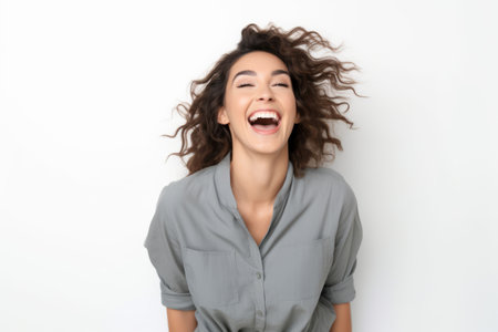 Portrait of happy young woman laughing with closed eyes on white backgroundの素材