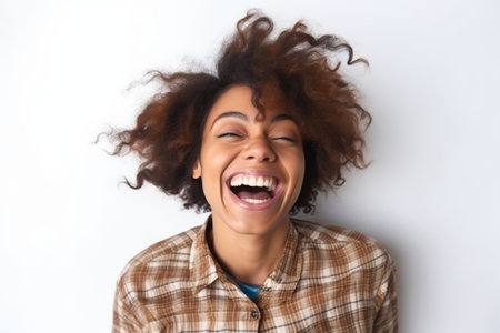 Portrait of beautiful young african american woman laughing against white backgroundの素材