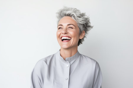 Portrait of a happy mature woman laughing and looking up over white backgroundの素材