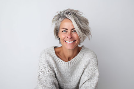 Portrait of a smiling middle-aged woman with short gray hair against white backgroundの素材