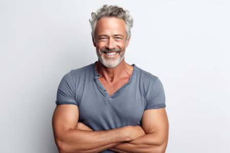 Portrait of handsome mature man standing with arms crossed against white backgroundの素材