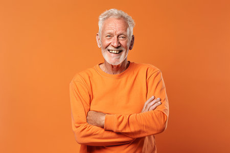 Portrait of a happy senior man in orange t-shirt on orange backgroundの素材