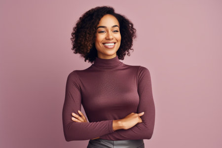 Portrait of a smiling young african american woman standing with arms folded against pink backgroundの素材