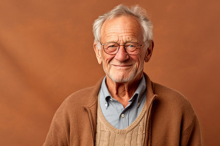 Portrait of a happy senior man in glasses on a brown backgroundの素材