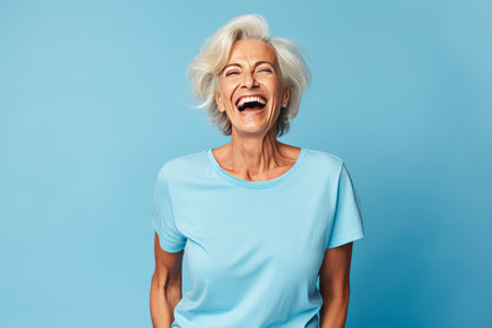 Portrait of a happy senior woman laughing at camera isolated over blue backgroundの素材