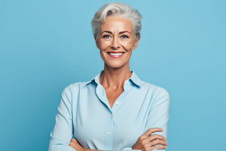 Portrait of happy senior woman looking at camera isolated on blue backgroundの素材