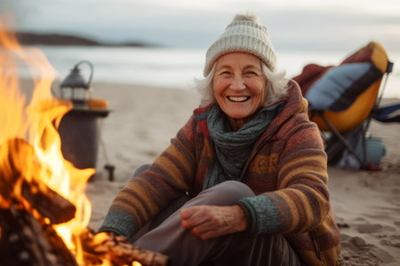 Portrait of happy senior woman sitting near bonfire on the beachの素材