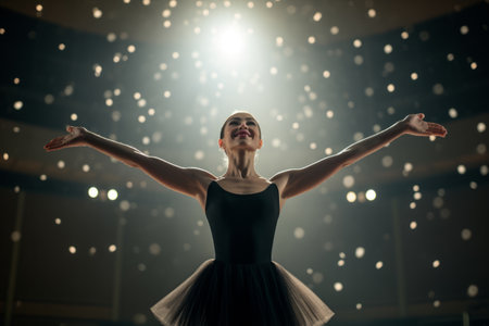 Young beautiful ballerina in black tutu and pointe shoes posing on stageの素材