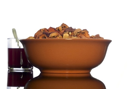 Brown ceramic bowl of homemade dried apples and a glass of transparent glass with a compote of the dried apples   on white background の写真素材