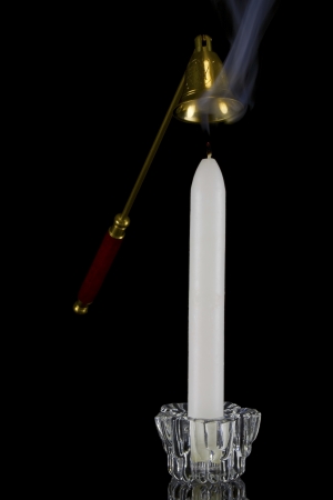 Candle in glass candlestick and candle snuffer on black backgroundの写真素材