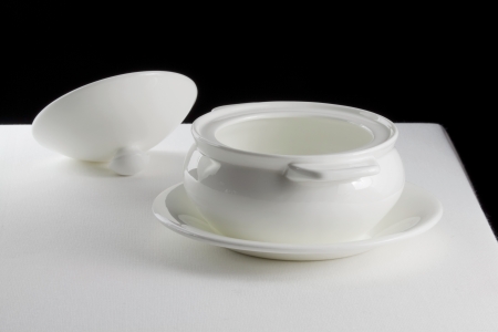 Tureen on a saucer and cover on a white tableclothの写真素材