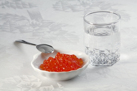 A small glass of vodka, salmon caviar in a plate for caviar and small spoon  の写真素材