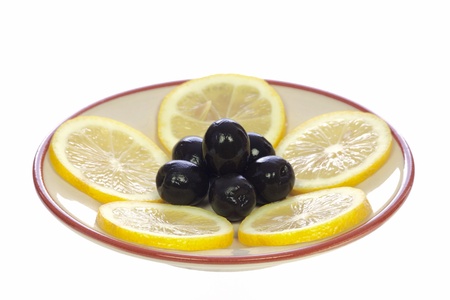 Lemons and olives on a ceramic saucer, isolated on white backgroundの写真素材
